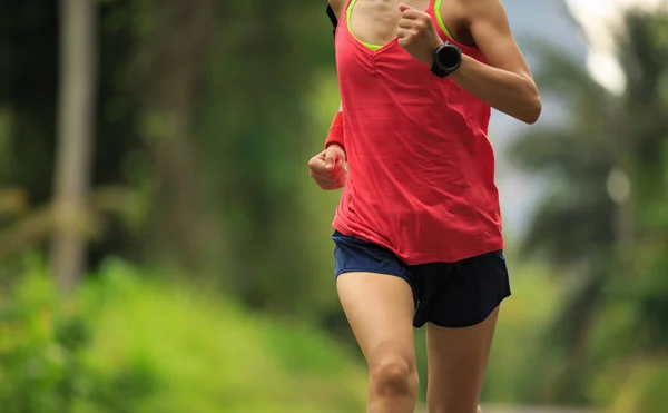 Mujer joven corriendo por sendero forestal — Foto de Stock