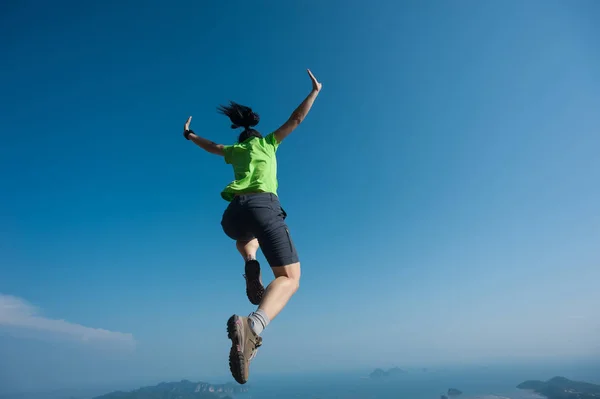 Young woman jumping on mountain peak — Stock Photo, Image