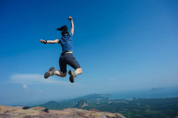 Junge Frau springt auf Berggipfel — Stockfoto