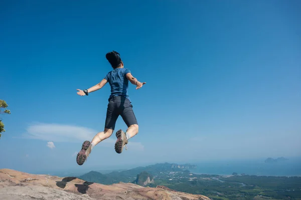Young woman jumping on mountain peak — Stock Photo, Image