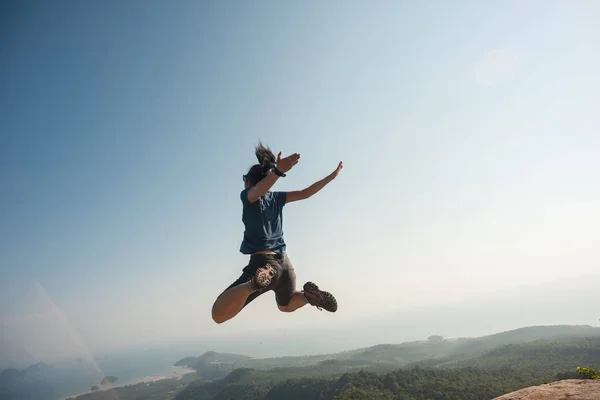 Mujer joven saltando en el pico de la montaña — Foto de Stock