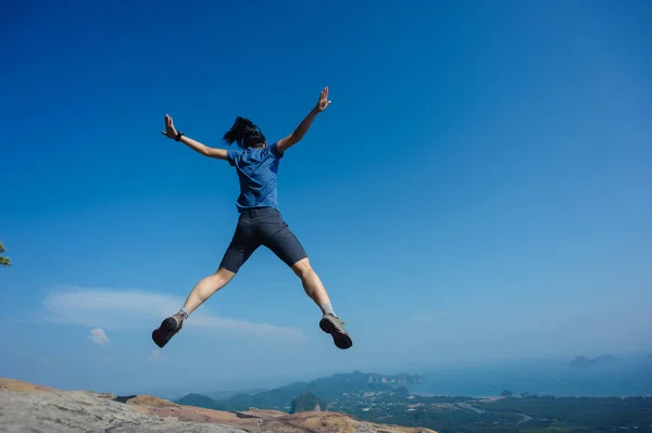 Junge Frau springt auf Berggipfel — Stockfoto