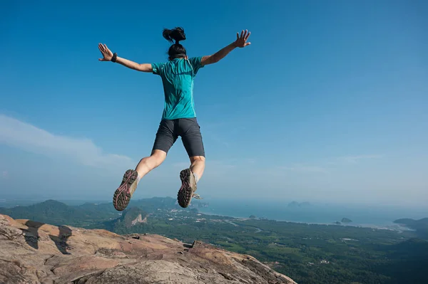 Jeune femme sautant sur le sommet de la montagne — Photo