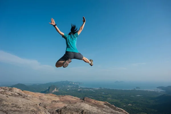 Jovem mulher pulando no pico da montanha — Fotografia de Stock