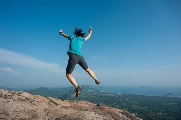 Jovem mulher pulando no pico da montanha — Fotografia de Stock