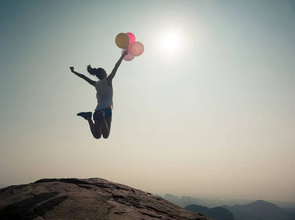 Mujer joven saltando con globos — Foto de Stock