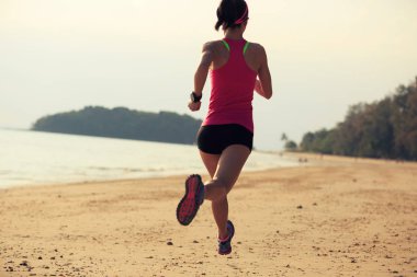 Genç kadın deniz kenarında koşuyor.