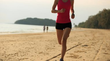 Genç kadın deniz kenarında koşuyor.