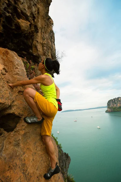 Donna arrampicata sulla scogliera sul mare — Foto Stock