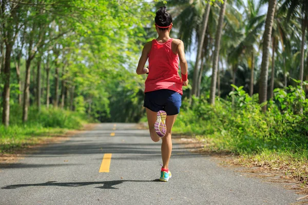 Mujer joven corriendo por sendero forestal —  Fotos de Stock