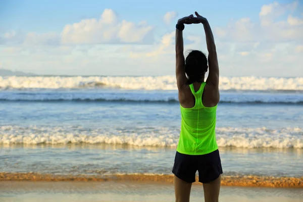 Jovem mulher esticando os braços antes de correr — Fotografia de Stock