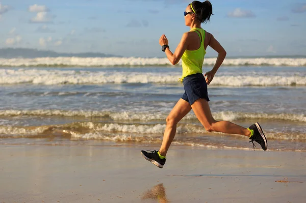 Mladá žena běží na písečné pláži — Stock fotografie
