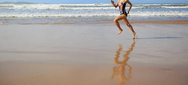 Mujer joven corriendo en la playa de arena — Foto de Stock