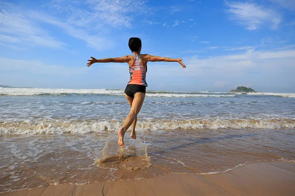 Jovem mulher correndo na praia — Fotografia de Stock