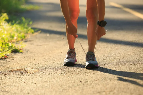 Mujer joven corredora atando cordones — Foto de Stock