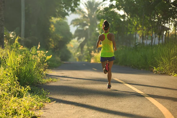 Mujer joven corriendo por sendero forestal —  Fotos de Stock