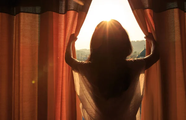 Mujer joven abriendo cortinas — Foto de Stock