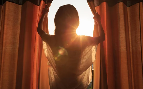 Ung kvinna öppna gardiner — Stockfoto