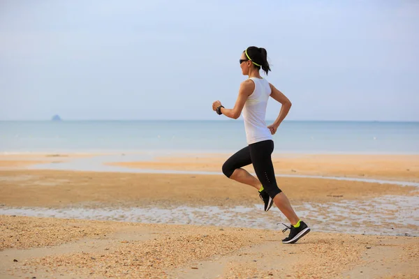 Mladá žena běží na písečné pláži — Stock fotografie