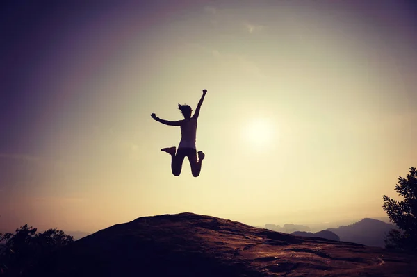 Женщина прыгает на вершину горы — стоковое фото