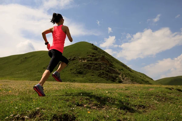 Jonge vrouw draait op grasland trail — Stockfoto