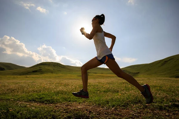 Jonge vrouw draait op grasland trail — Stockfoto