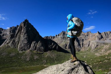 Dağlarda yürüyüş yapan genç bir kadın.  