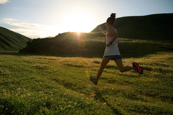 Jonge vrouw draait op grasland trail — Stockfoto