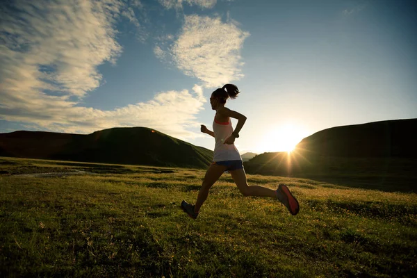 Jovem mulher correndo em trilha pastagens — Fotografia de Stock