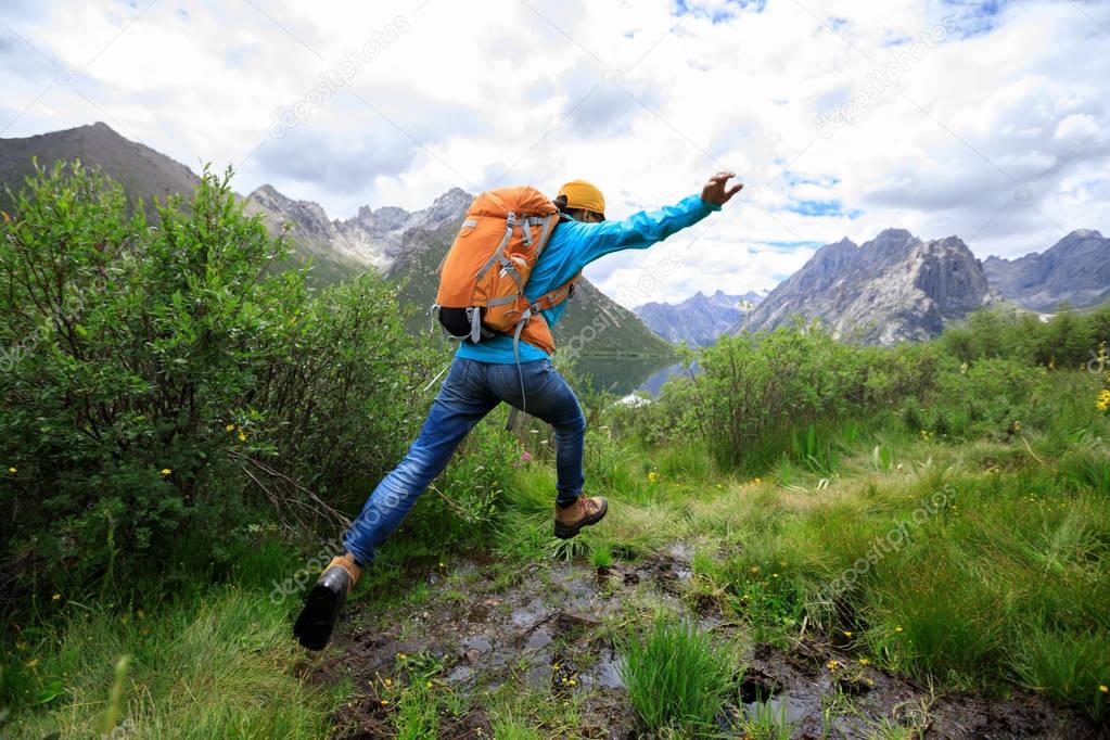 Young woman jumping over marsh in mountains