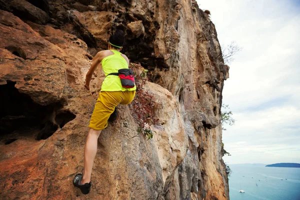 若い女性の海辺の崖の登山 — ストック写真