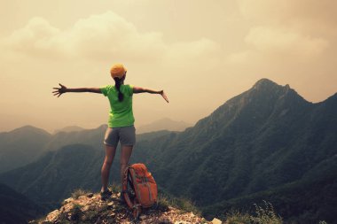 dağ tepesinde Kollarını açarak başarılı kadın uzun yürüyüşe çıkan kimse