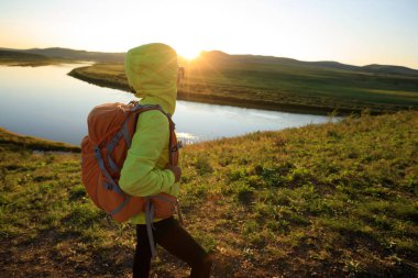 Nehir kenarında dağda hiking sırt çantası olan kadın