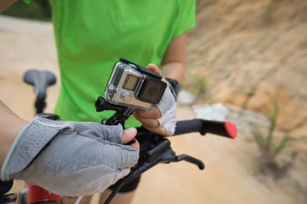 Young woman mounting action camera on mountain bike