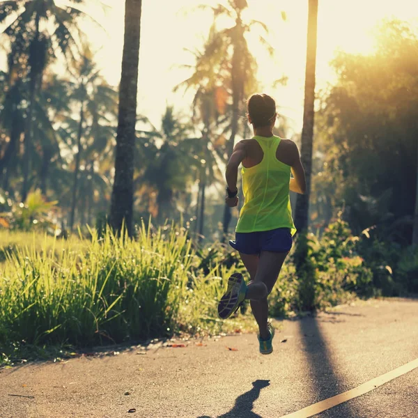 Mujer joven corriendo por sendero forestal — Foto de Stock