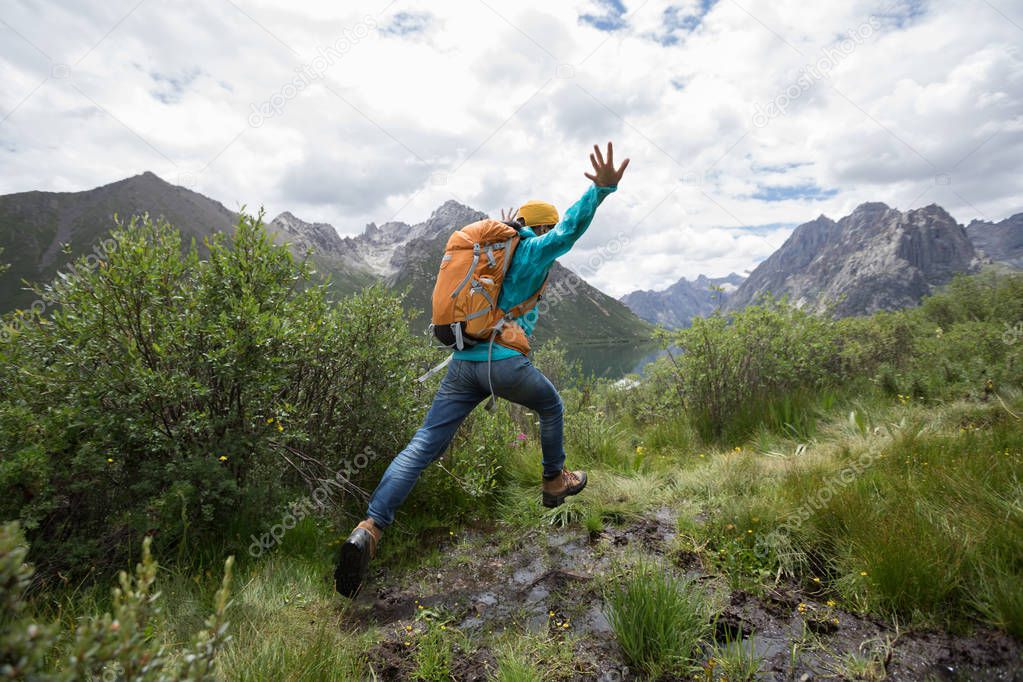 backpacking woman jumping in mountains