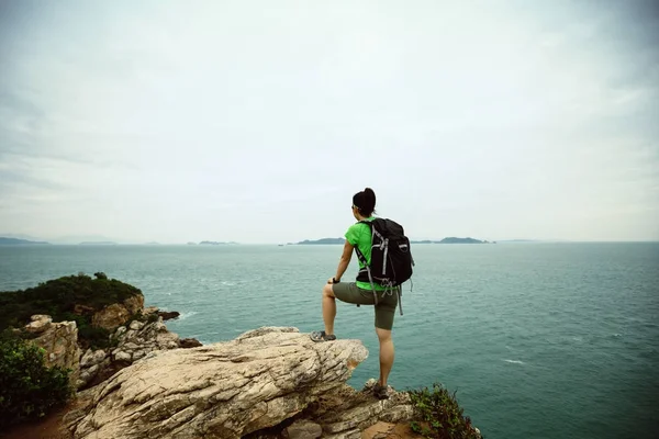 Mujer disfrutando de la vista en acantilado junto al mar —  Fotos de Stock