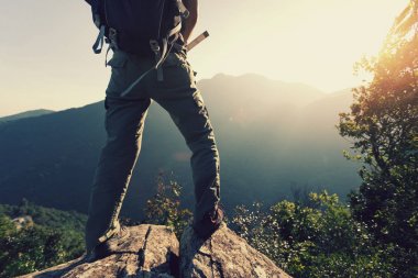 güneşin doğuşunu dağın tepesinde duran genç kadın backpacker