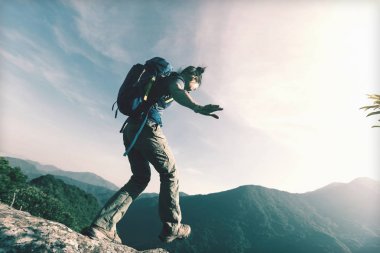  uçurumun kenarına kadar dağın tepesinde yürüyen genç kadın uzun yürüyüşe çıkan kimse