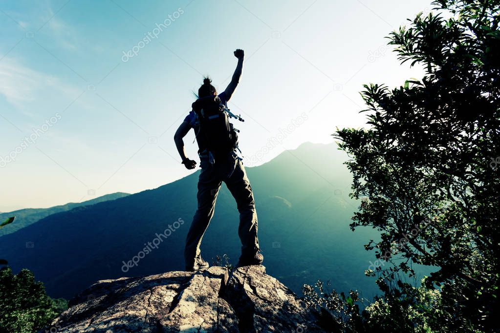 successful young woman enjoying the view on mountain cliff