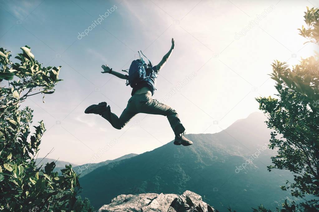 young woman jumping on cliff 