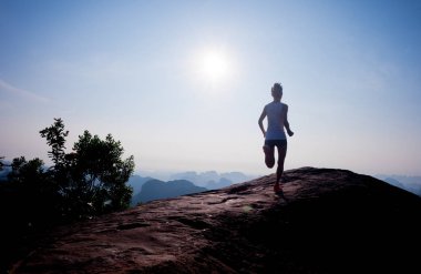 Gündoğumu dağın tepesinde çalışan genç kadın  