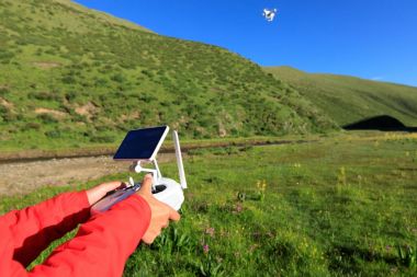 Gökyüzünde uçan dronun uzaktan kumanda kullanan kadın