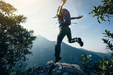 başarılı genç kadın backpacker Cliff üzerinde atlama