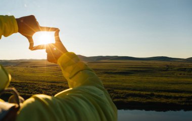 insan elinin üzerinde günbatımı gökyüzü kalp şeklinde işaret yapma