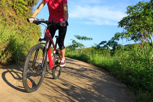 female cyclist riding mountain bike on country road