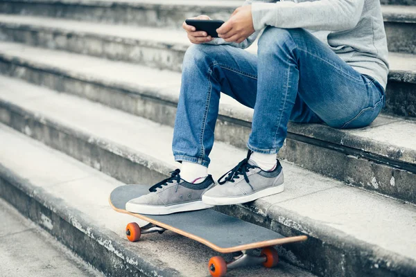 滑板使用智能手机 而坐在城市楼梯 — 图库照片