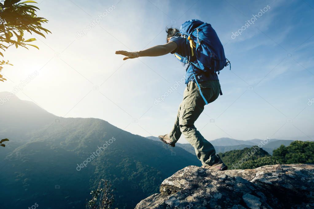 brave woman hiker walking to the edge on mountain top