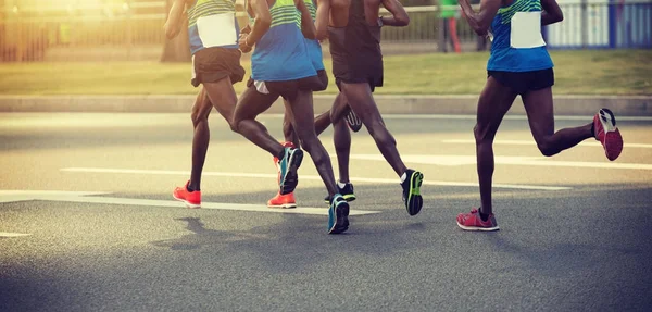 legs of marathon runners running on city road