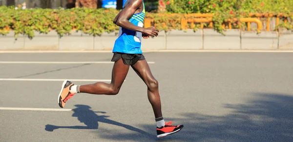 legs of marathon runner running on city road